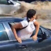 鉄砲水で流される車からはい這い出ようとする女性（スペイン）